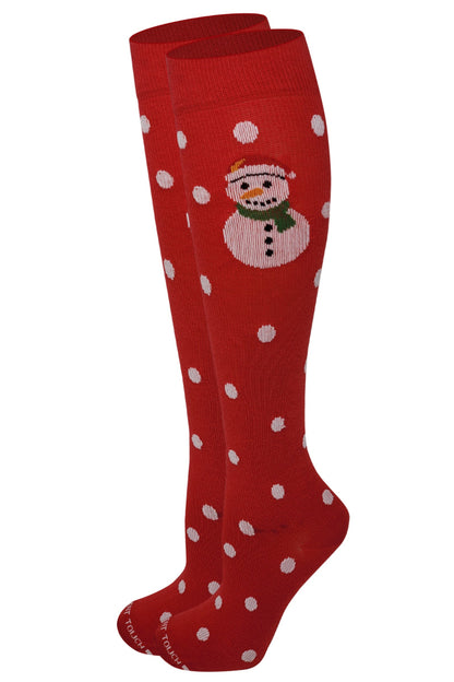 A pair of red knee-high socks with white polka dots and a Christmas design featuring a snowman.